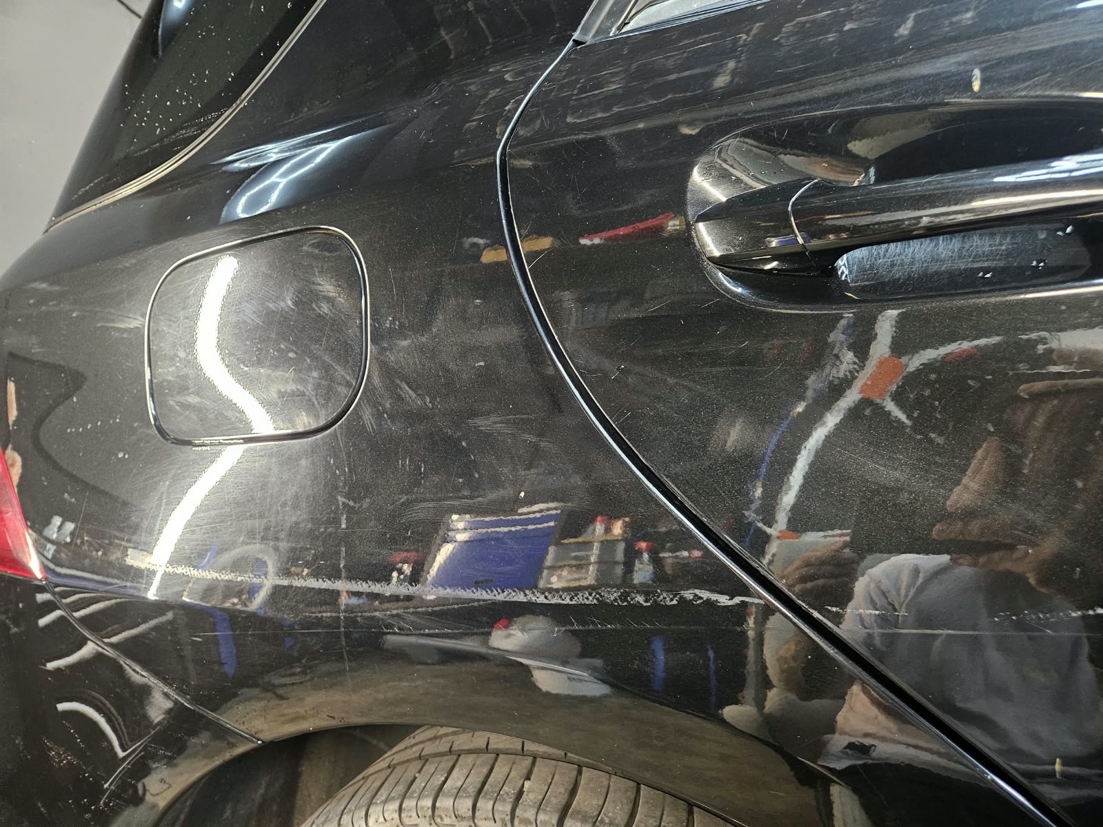 Hinteres Seitenteil eines schwarzen Autos mit feinen Kratzern vor der Politur
