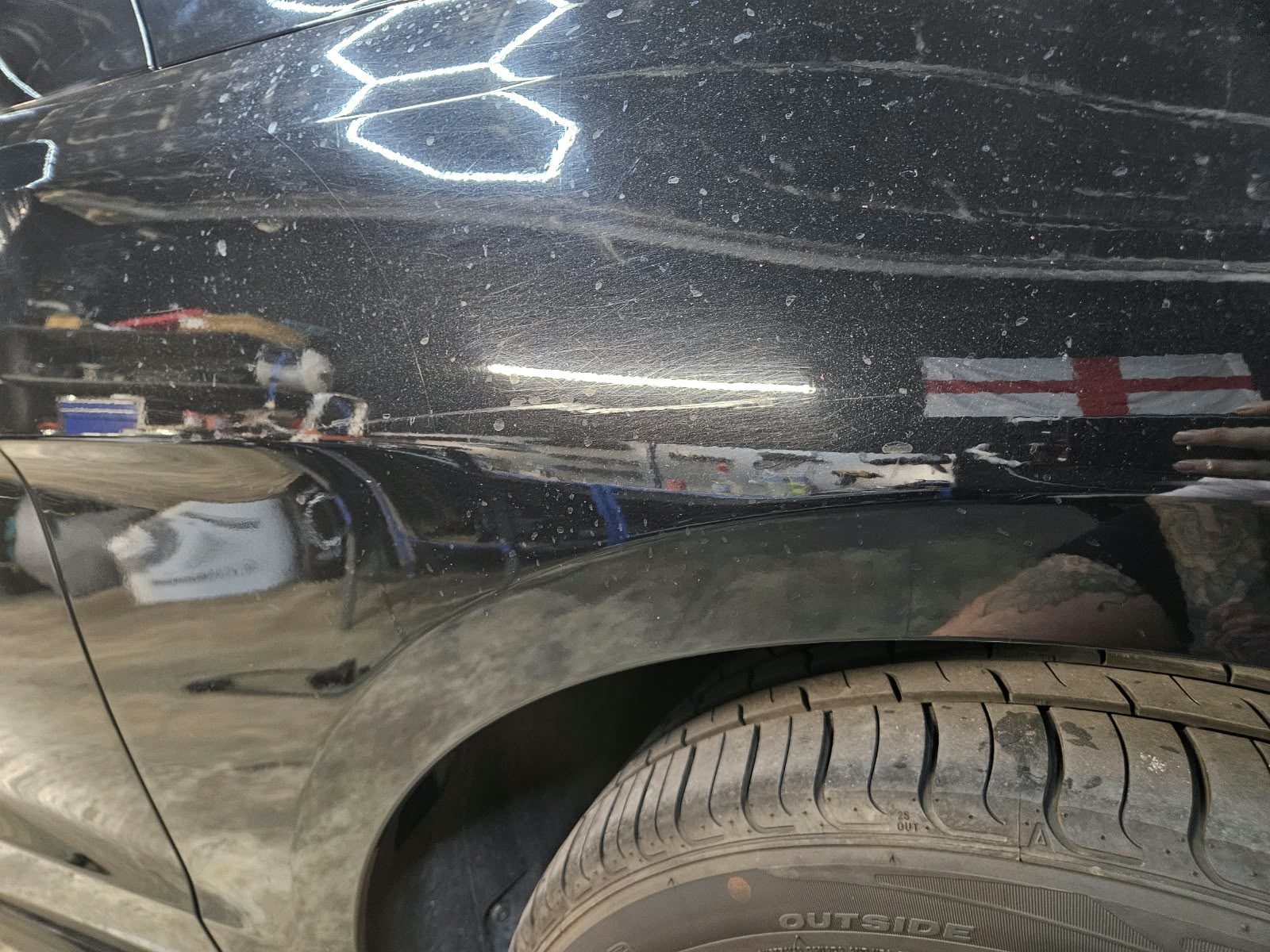 Radlauf eines schwarzen Autos mit sichtbaren Waschkratzern vor der Politur
